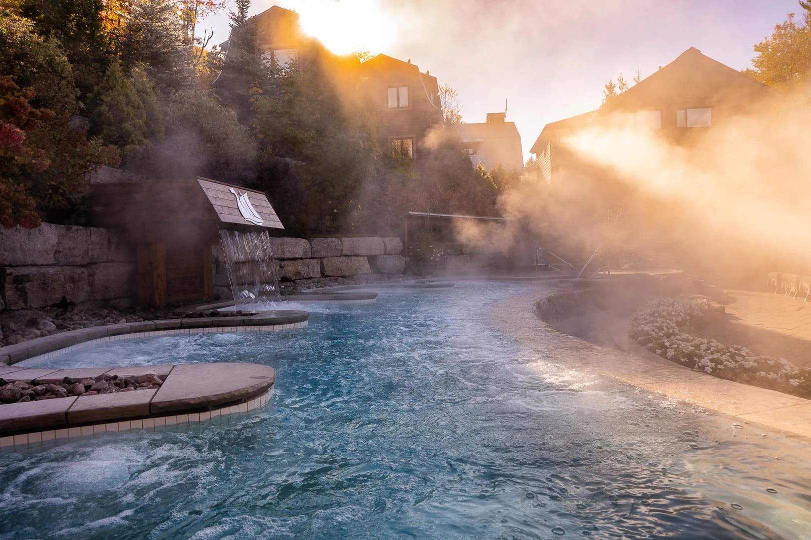 Bassins thermaux fumants du Scandinave Spa au lever du soleil.